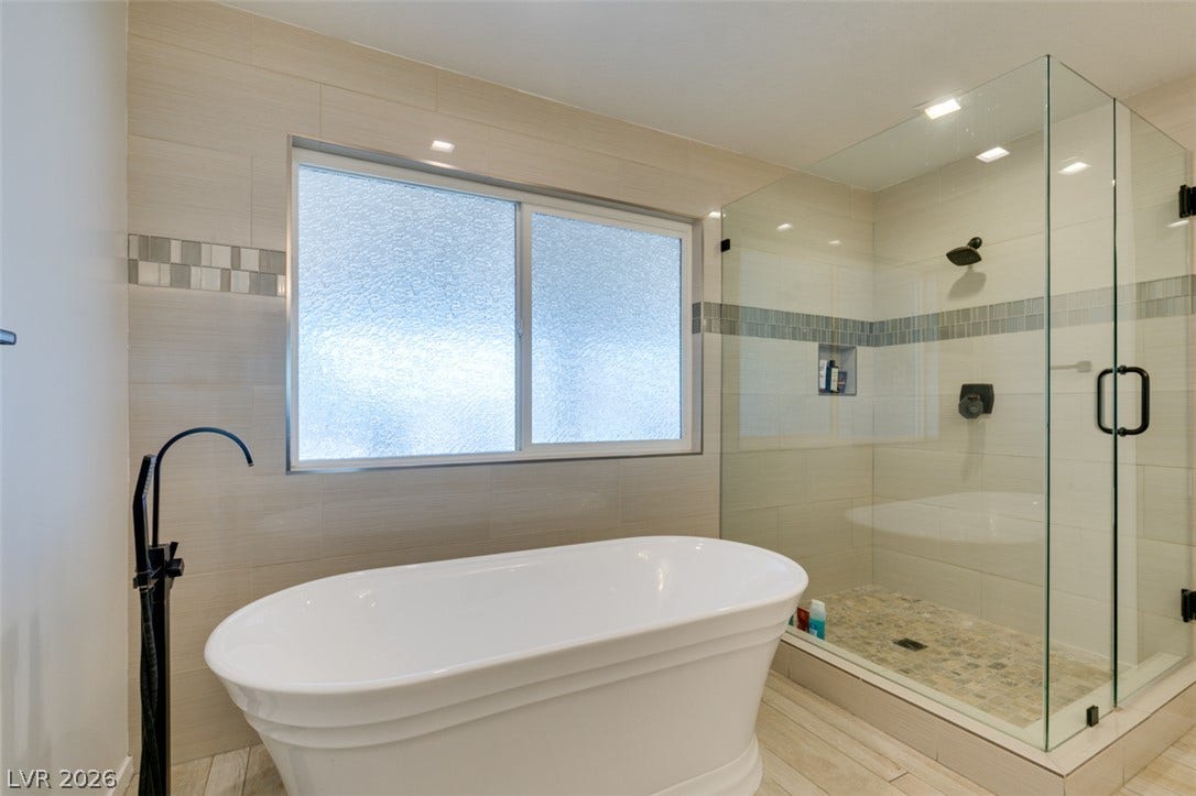 2246 Almart Circle, Henderson, NV 89014 Sleek modern tiling and a freestanding soaking tub elevate this bright primary bathroom.