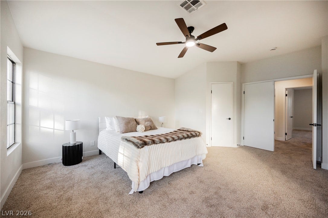 4877 Fiesta Lakes Street, Las Vegas, NV 89130 Plush carpeting anchors this spacious bedroom filled with natural light from a large window.