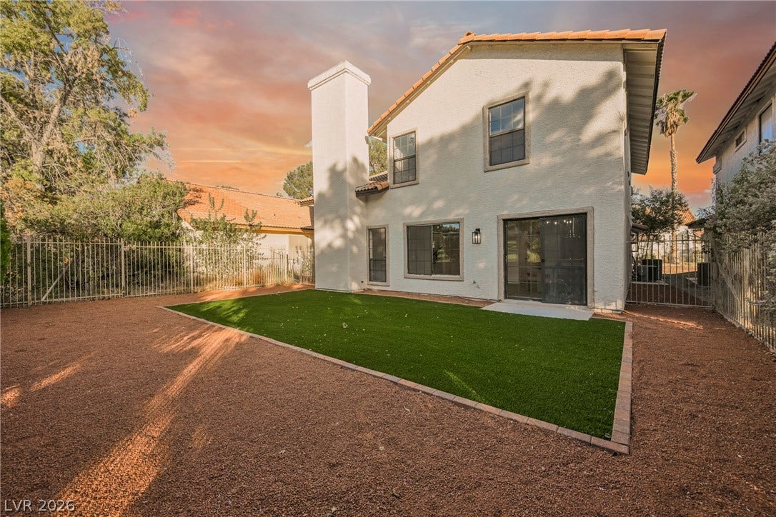 4877 Fiesta Lakes Street, Las Vegas, NV 89130 Fenced backyard features zero-maintenance turf alongside a towering stucco fireplace chimney.