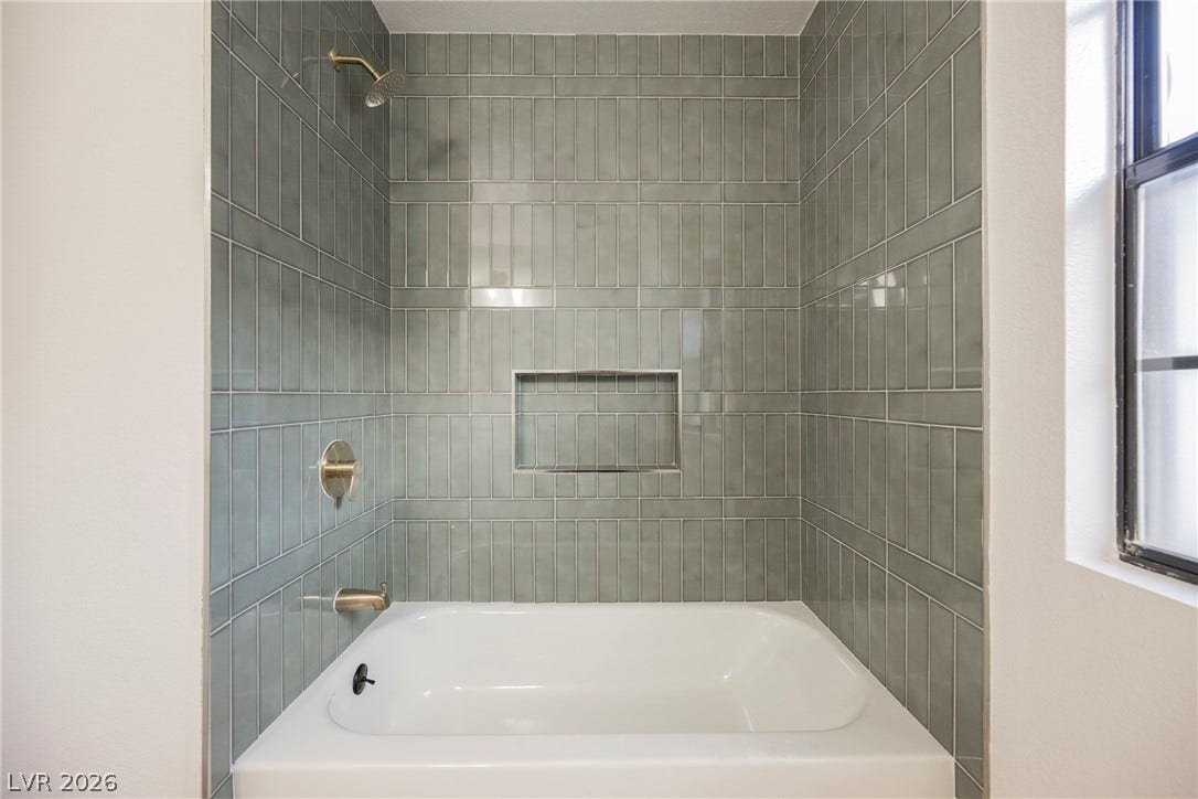 4877 Fiesta Lakes Street, Las Vegas, NV 89130 Sleek vertical tiling frames a built-in tub and shower combo under natural window light.