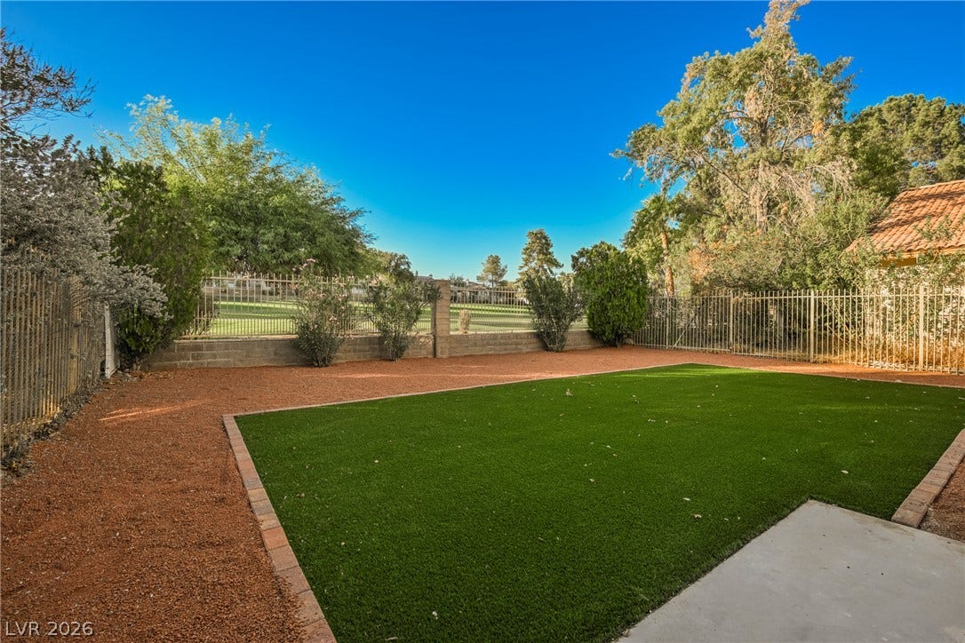 4877 Fiesta Lakes Street, Las Vegas, NV 89130 An inviting backyard features low-maintenance synthetic turf bordered by desert landscaping and secure fencing.