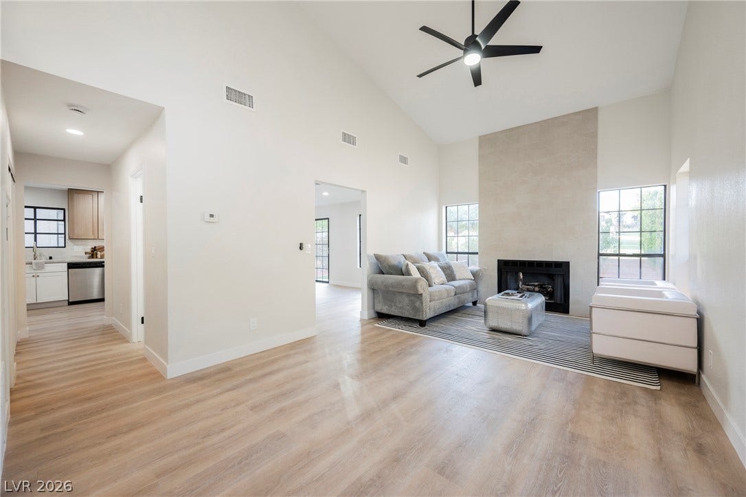 4877 Fiesta Lakes Street, Las Vegas, NV 89130 High ceilings and a fireplace anchor this open living area with wood-style flooring.