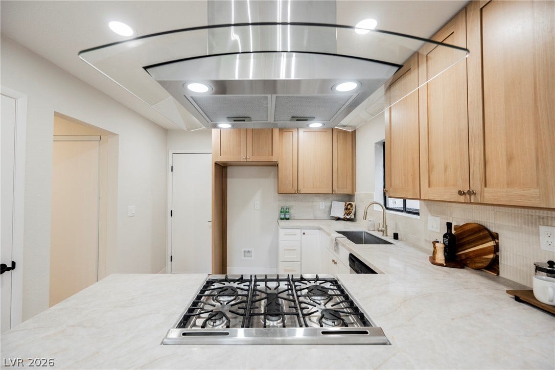 4877 Fiesta Lakes Street, Las Vegas, NV 89130 Natural wood cabinets pair with stone countertops and a modern gas cooktop in this kitchen.