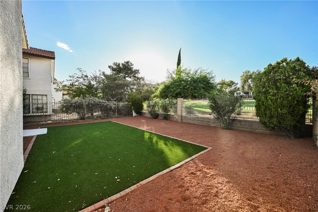 4877 Fiesta Lakes Street, Las Vegas, NV 89130 A low-maintenance yard features a neat synthetic lawn bordered by gravel and fencing.