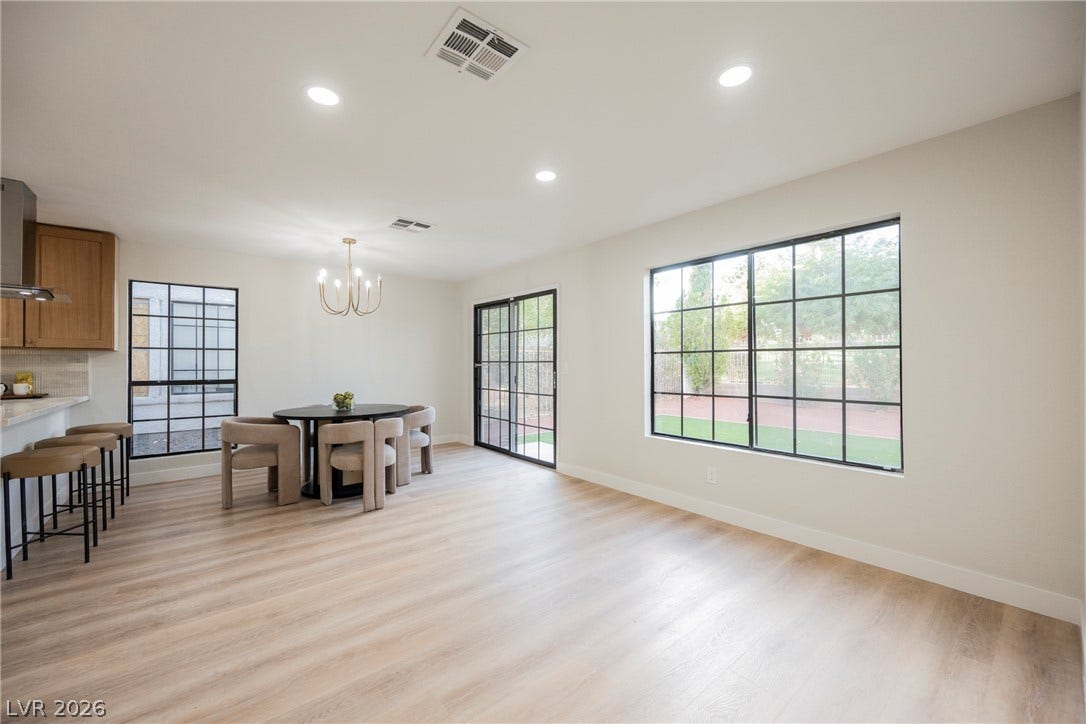 4877 Fiesta Lakes Street, Las Vegas, NV 89130 A spacious dining area with wood-look flooring and multiple grid windows looking outside.