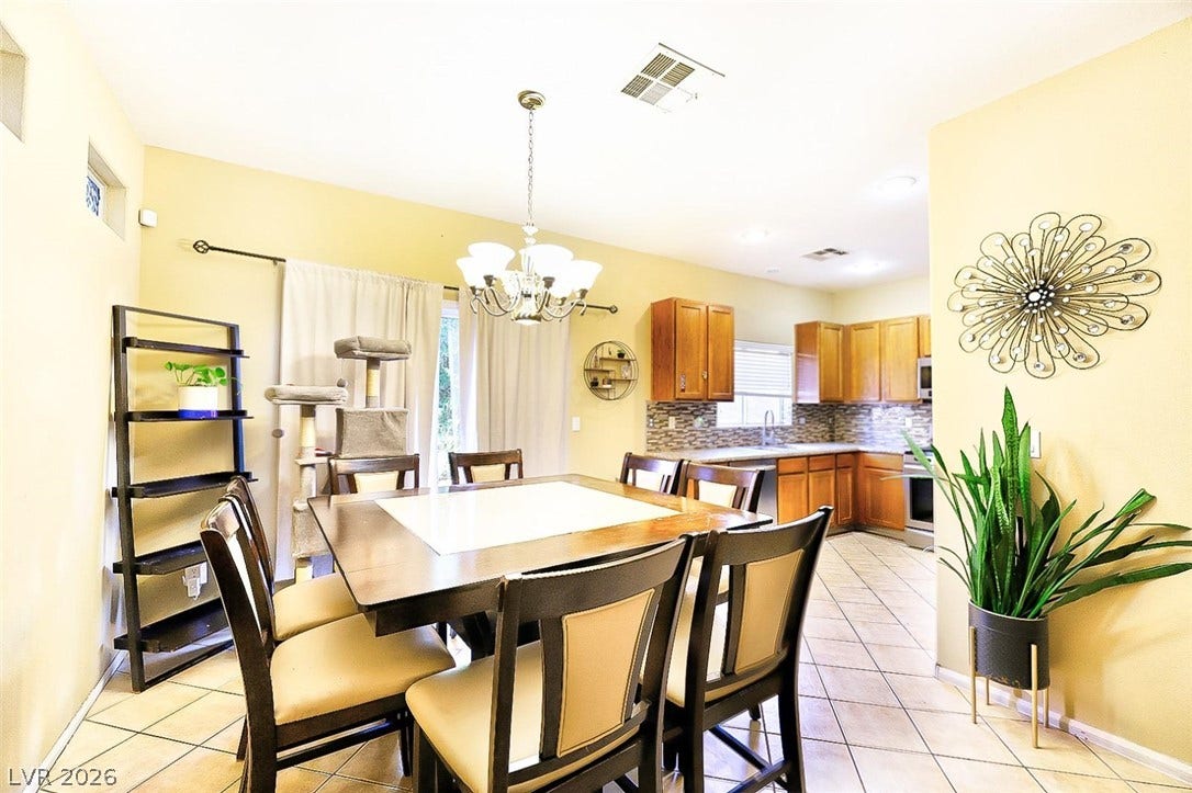 Tiled flooring and warm cabinetry define this integrated kitchen and dining space.