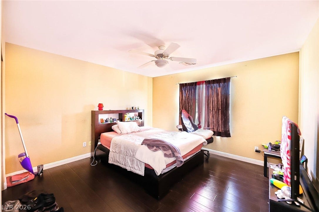 Rich dark wood flooring anchors this comfortable bedroom space illuminated by natural light.