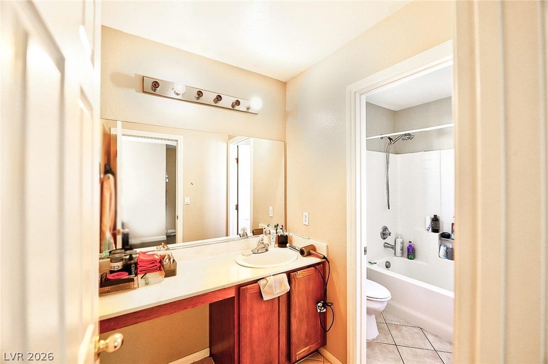 A classic vanity area connects seamlessly to an adjacent bathroom with tiled flooring.