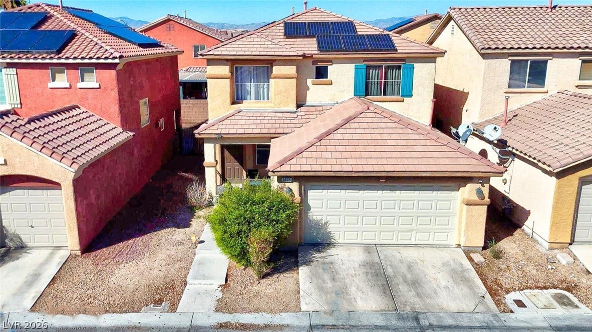 Solar panels top this two-story residence featuring stucco walls and a tile roof.