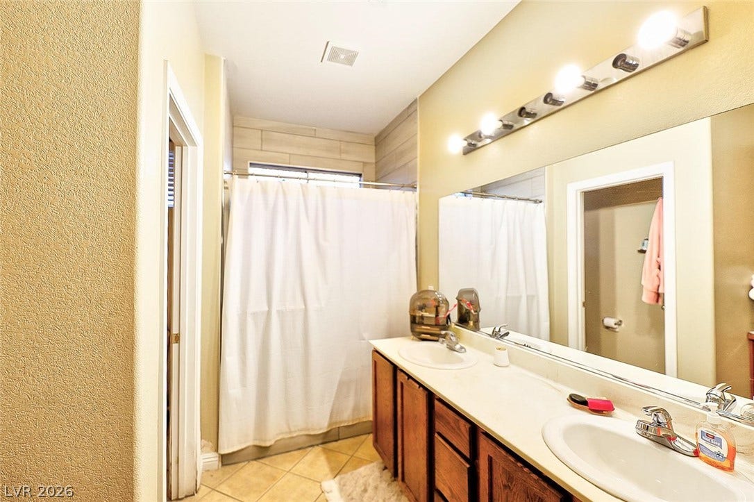 A spacious double vanity and tiled flooring anchor this functional secondary bathroom.