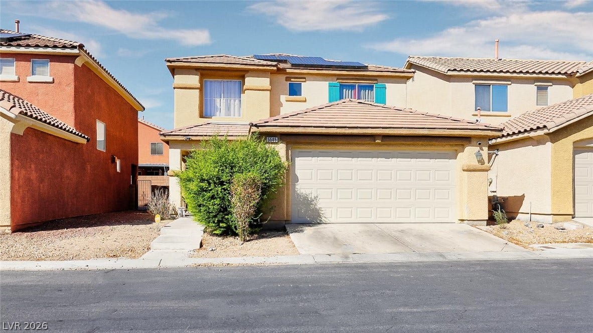 Mediterranean-inspired styling pairs with an attached garage under a sunny blue sky.