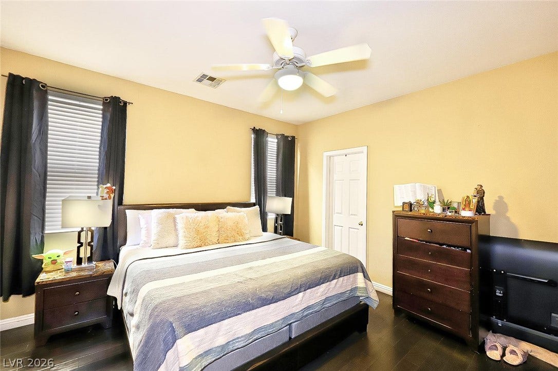 Rich hardwood flooring anchors this inviting bedroom, illuminated by ample natural light.
