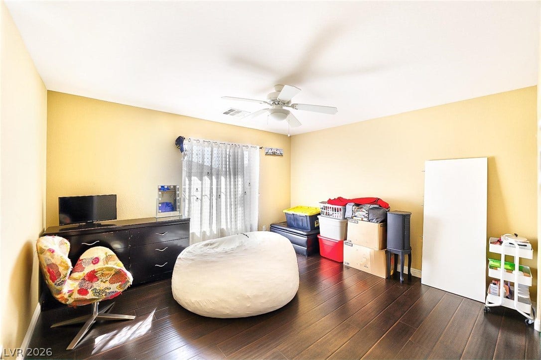 Rich dark wood floors ground this flexible secondary room illuminated by a large central window.