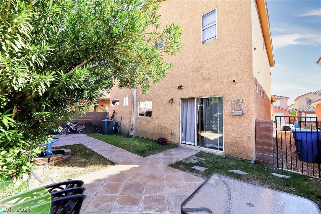 Paved pathways wind through a private fenced backyard framed by classic stucco exterior walls.