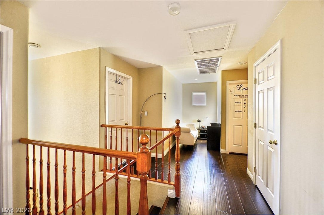 Gleaming hardwood floors and a wooden banister define this upper-level hallway space.