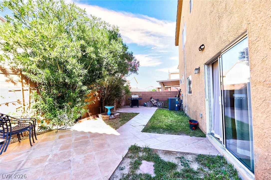 Tiled pathways wind through a private backyard enclosed by stucco walls and mature greenery.