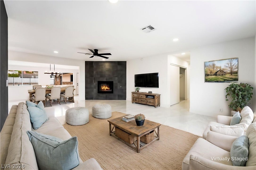 A modern fireplace with dark surround highlights this light-filled living space with tile flooring.