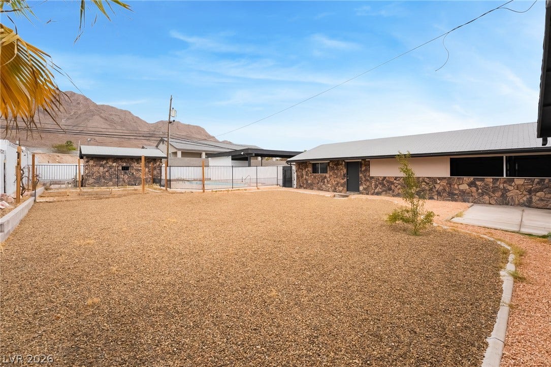 Scenic mountain vistas frame this sprawling desert-landscaped backyard with stone-clad architectural details.