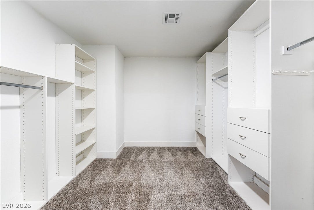 Ample built-in shelving and soft carpeting define this spacious walk-in closet.