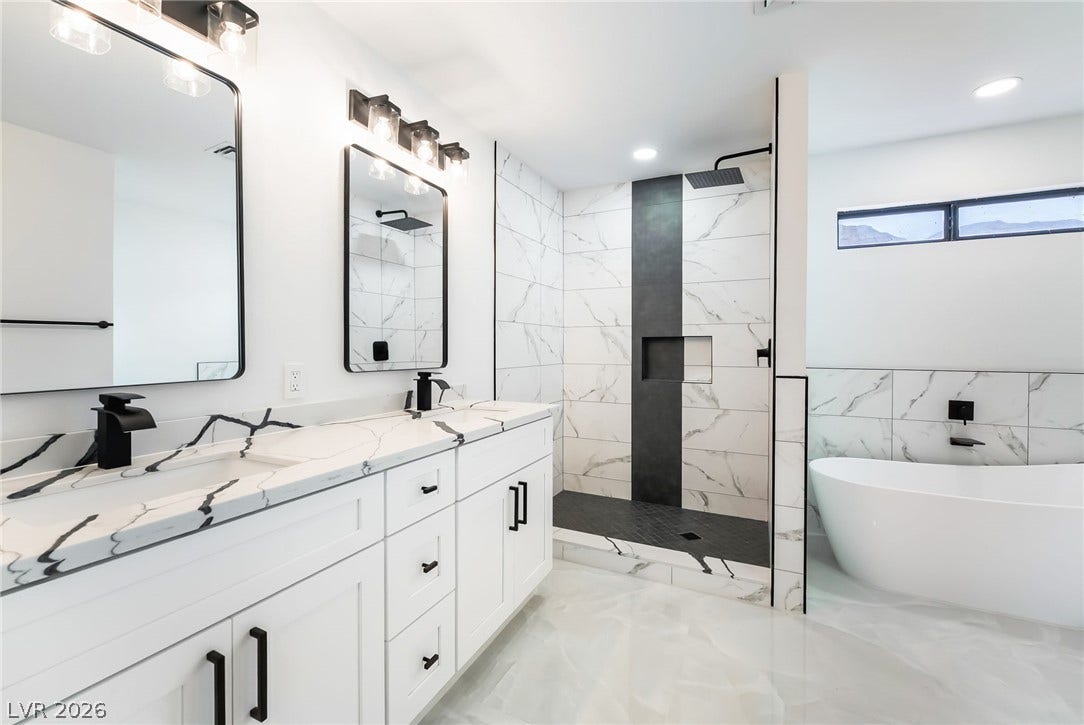 A freestanding tub and walk-in shower elevate this sleek double vanity bathroom.