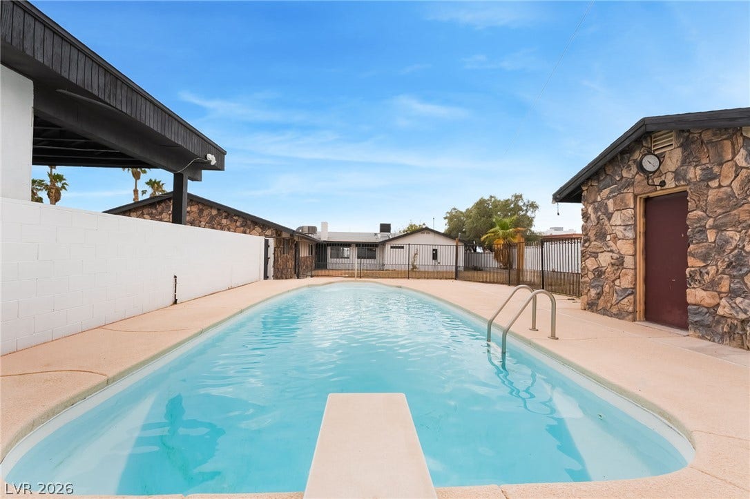 A spacious concrete patio surrounds the swimming pool, complete with a diving board.