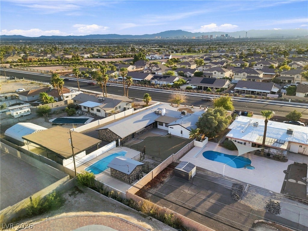 An aerial perspective showcases a spacious backyard with a private pool against distant mountain silhouettes.