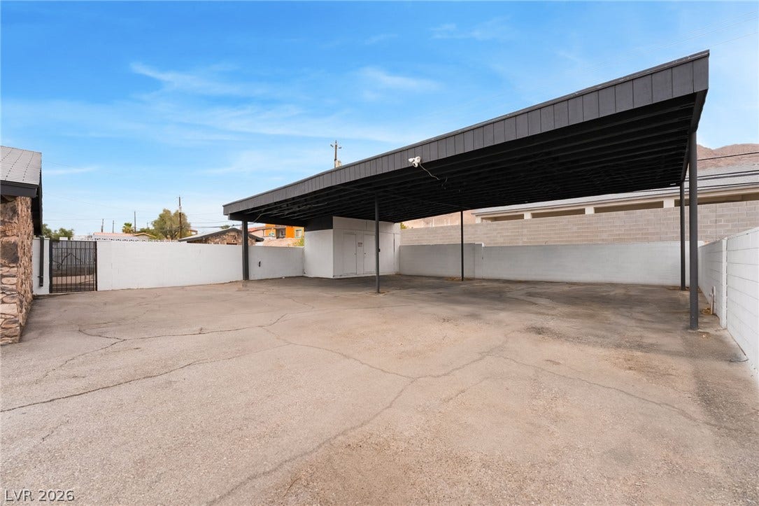 A spacious covered carport provides sheltered parking alongside a wide paved driveway.
