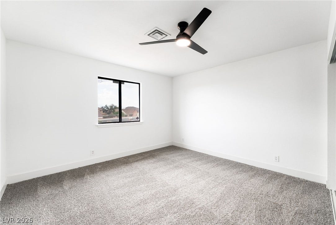 A minimalist bedroom displays clean white walls and textured wall-to-wall carpeting.