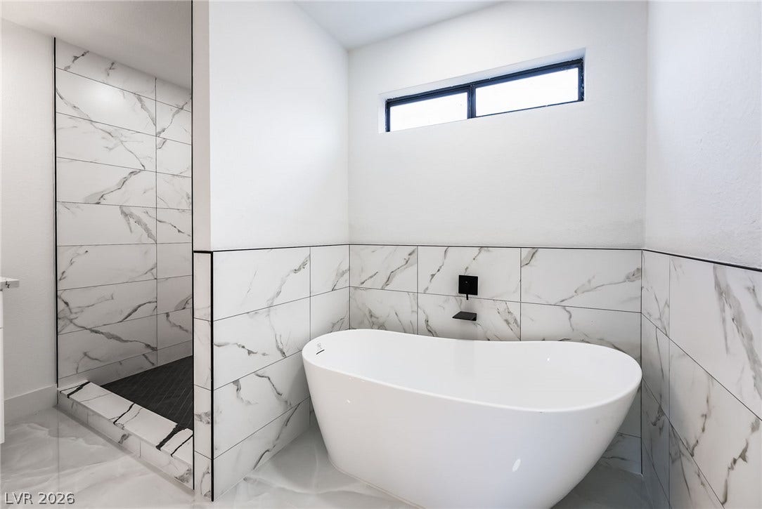 A deep soaking tub highlights this modern bathroom with elegant tile surrounds.