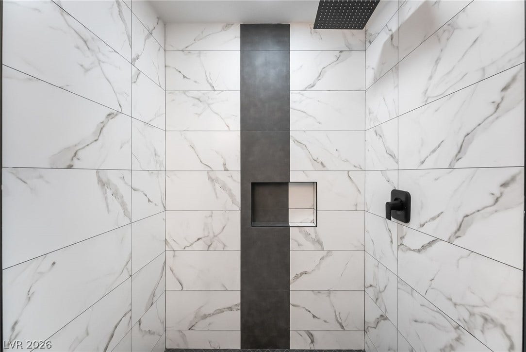 Elegantly veined marble-patterned tile lines this modern shower with a contrast stripe and built-in niche.