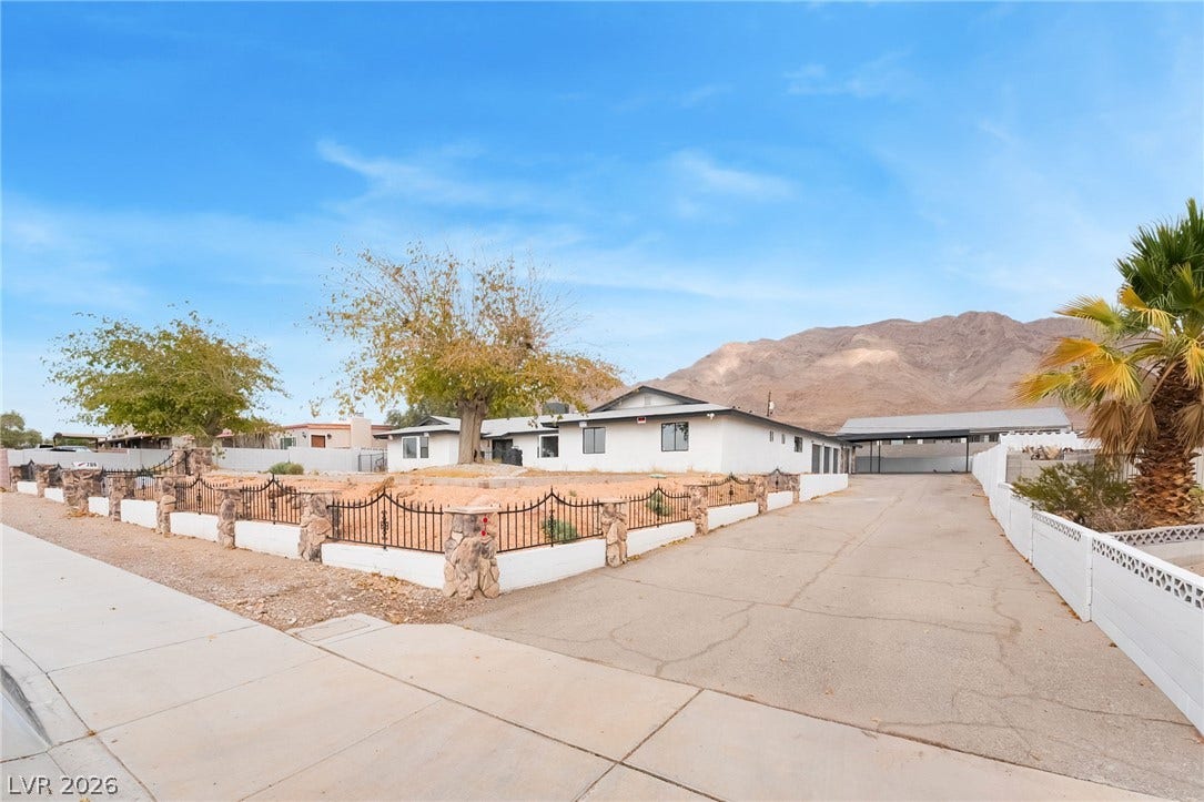 Dramatic mountain vistas rise behind this single-story home featuring a gated perimeter and wide driveway.