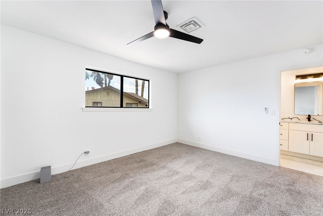 Clean lines and plush neutral carpeting define this airy bedroom with adjacent bath access.
