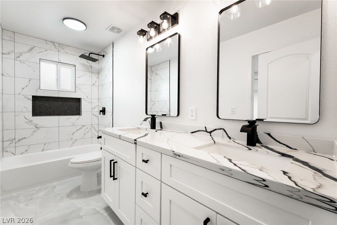 Crisp white cabinetry pairs with elegant stone countertops in a modern bathroom layout.