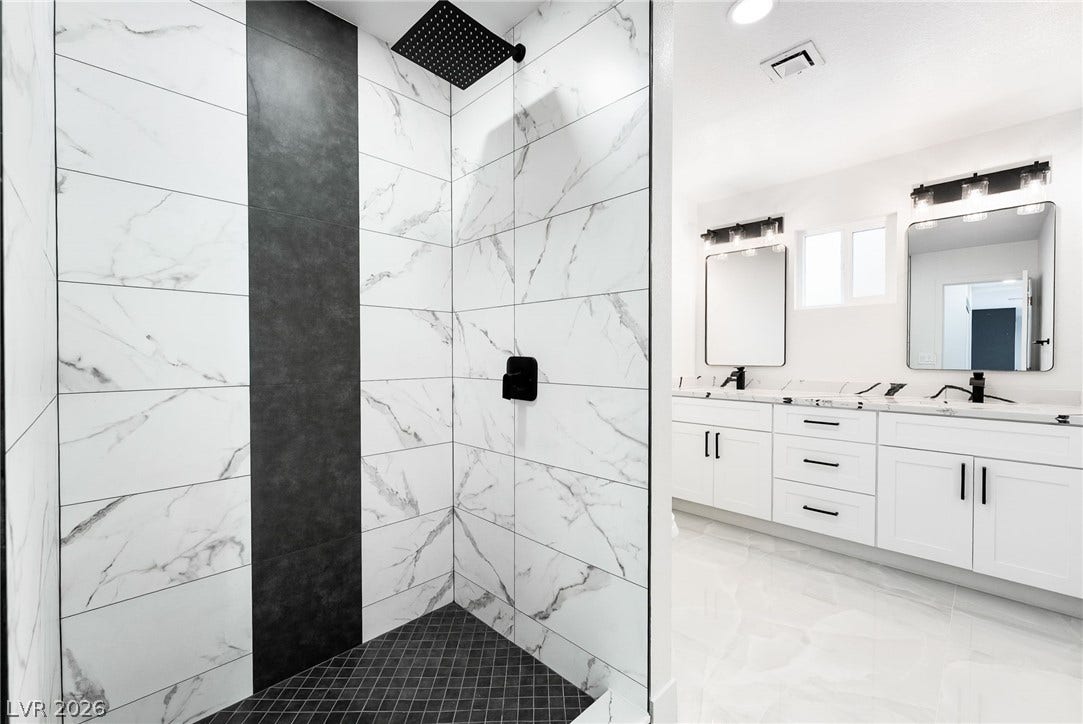 Gleaming custom tile accents and a dual vanity define this modern, spa-like bathroom.