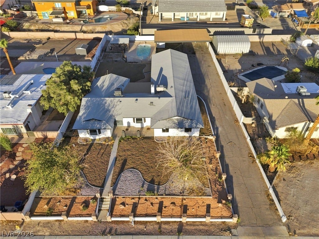 An aerial perspective showcases the structured front landscaping and metal roofing of this ranch-style home.