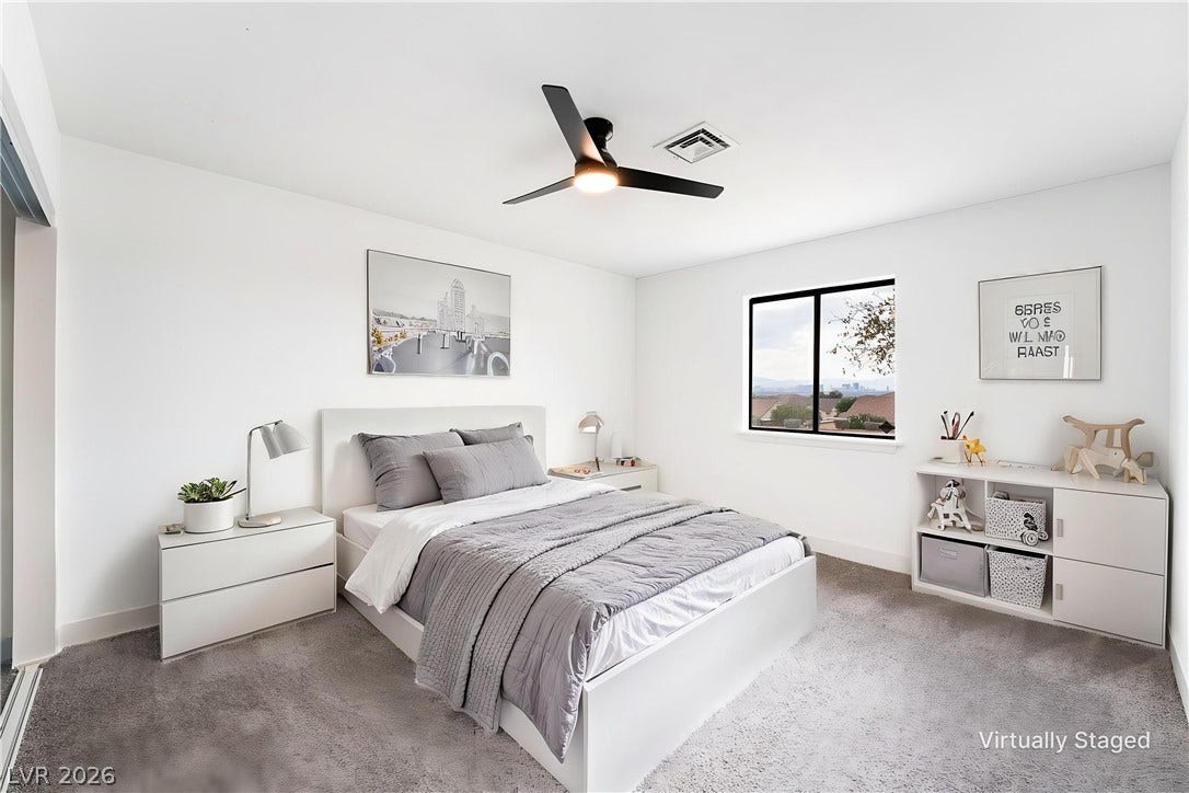 Plush carpeting and a wide window frame city views in this modern bedroom.