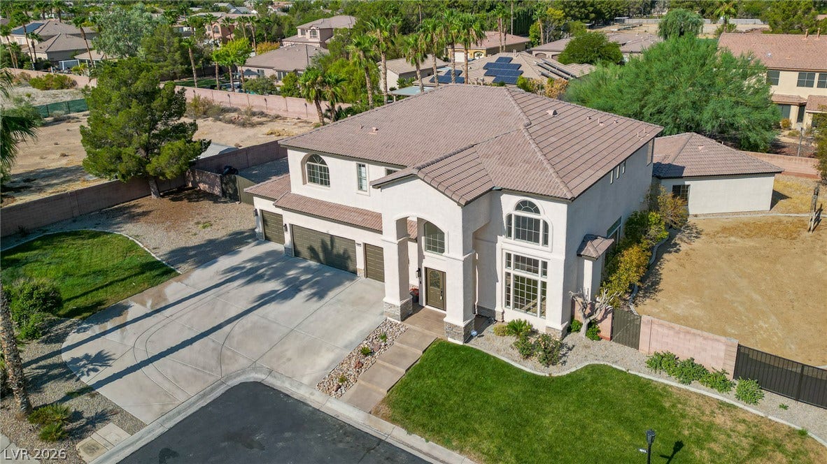 An elegant stucco exterior pairs with a tile roof on a manicured corner lot.