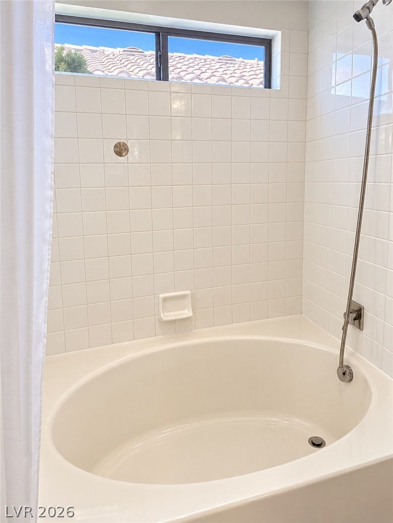 3925 Lilac Haze Street, Las Vegas, NV 89147 Tiled walls and a high transom window frame this deep oval soaking tub.