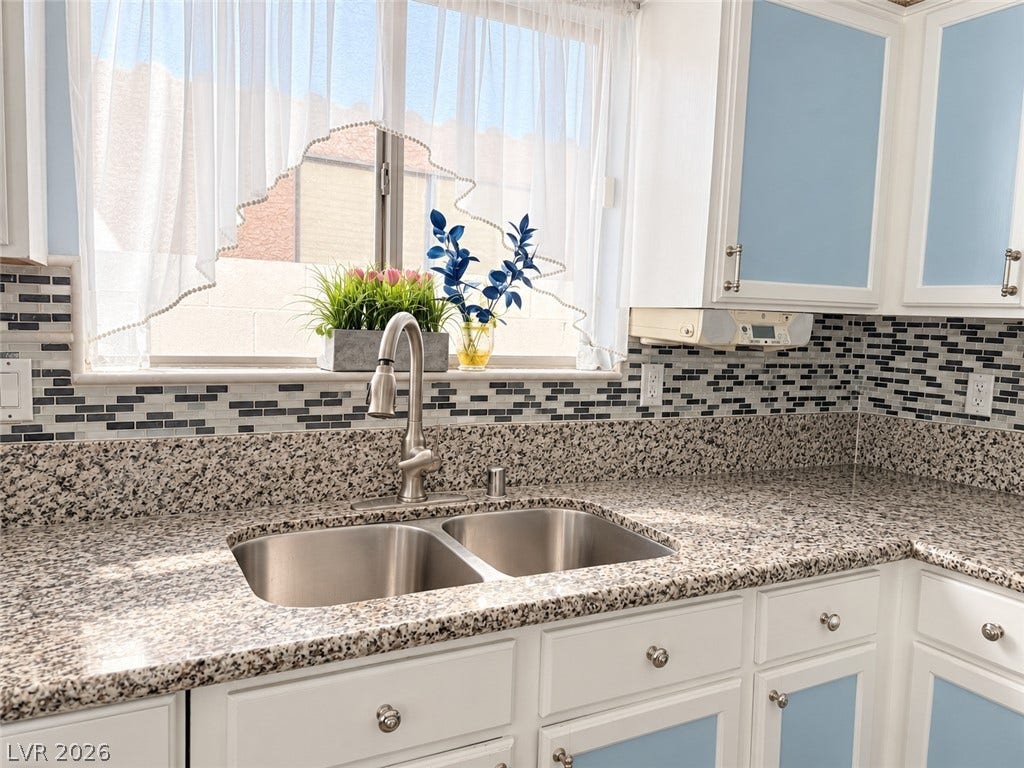 3925 Lilac Haze Street, Las Vegas, NV 89147 Polished granite countertops surround a dual-basin stainless steel sink beneath a wide window.