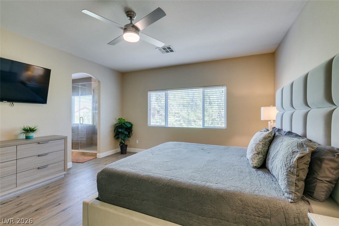 3166 E Eldorado Lane, Las Vegas, NV 89120 Smooth wood-look flooring and an arched doorway leading to an en suite bath ground this bedroom.