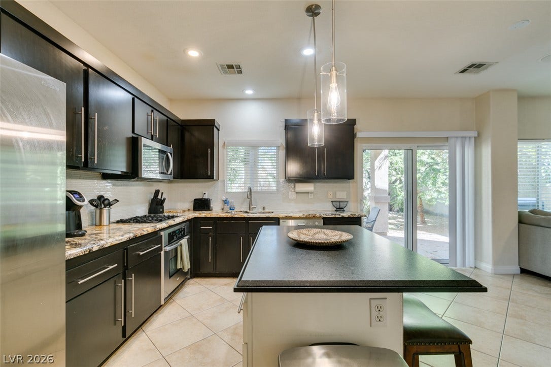 3166 E Eldorado Lane, Las Vegas, NV 89120 Gleaming stone countertops and dark cabinetry define this modern kitchen with a central island.