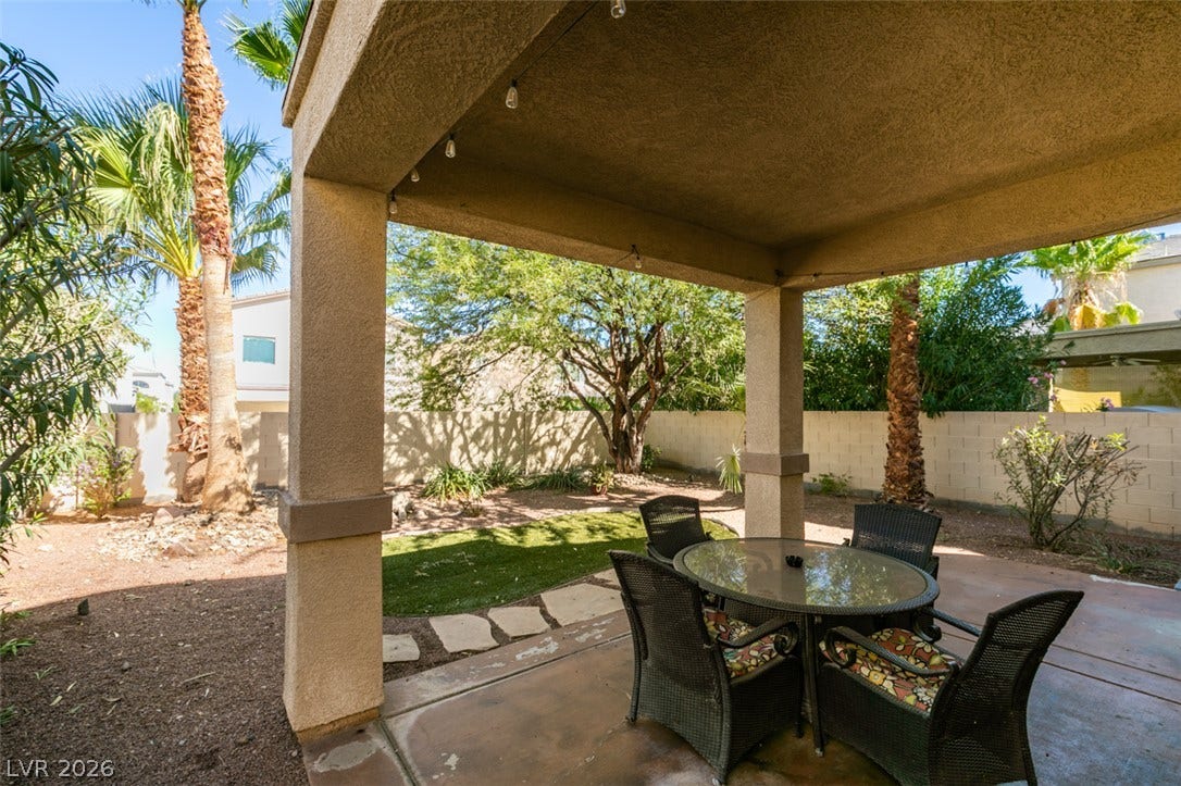 3166 E Eldorado Lane, Las Vegas, NV 89120 An inviting covered patio overlooks the fenced backyard complete with palm trees and green lawn.