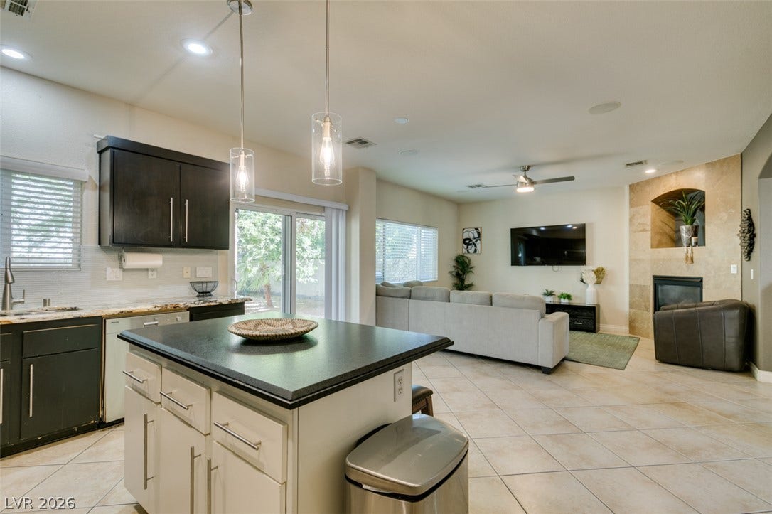 3166 E Eldorado Lane, Las Vegas, NV 89120 An open floorplan seamlessly connects the kitchen island to the living area and stone fireplace.