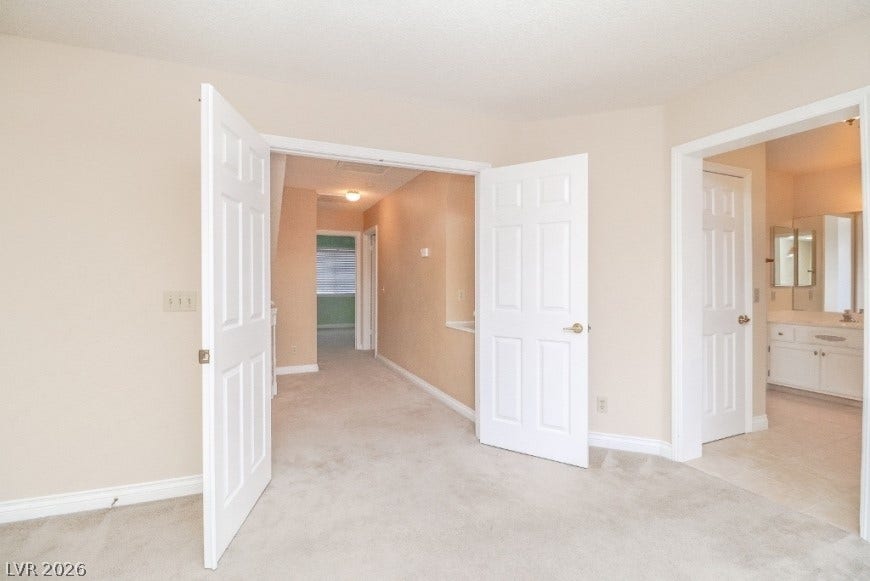 1429 Hawkwood Road, Henderson, NV 89014 Double doors open to a spacious primary suite featuring soft carpet and an adjacent bathroom.