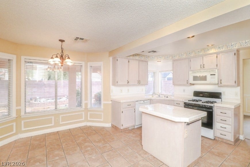 1429 Hawkwood Road, Henderson, NV 89014 An open kitchen and dining area features tile flooring, built-in cabinetry, and a central island.