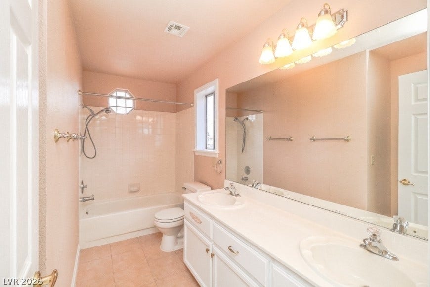 1429 Hawkwood Road, Henderson, NV 89014 Double vanities and a tiled tub shower combination anchor this functional bathroom space.