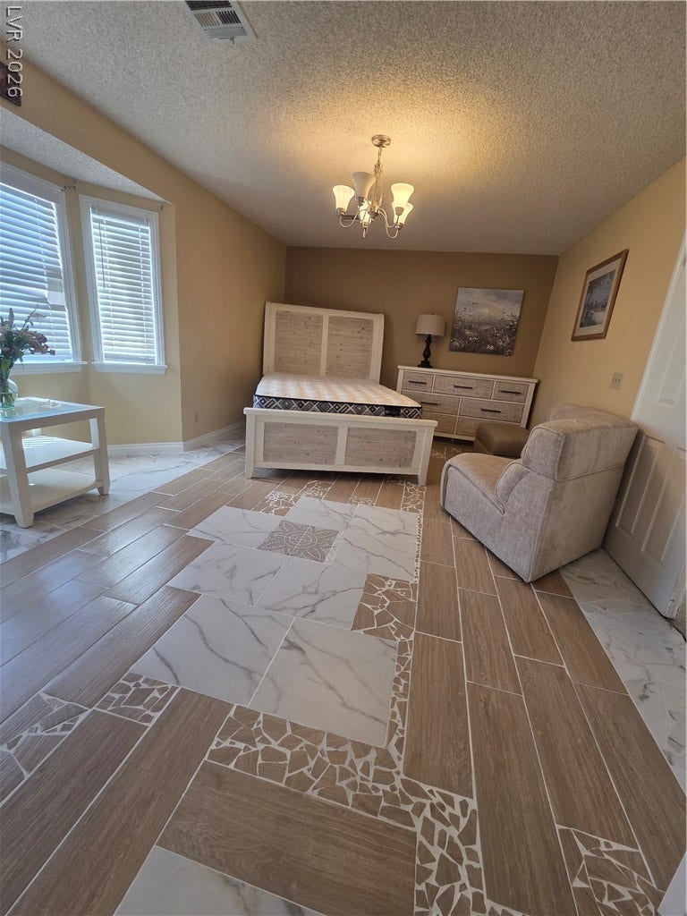 1429 Hawkwood Road, Henderson, NV 89014 Ornate custom tile flooring anchors this well-appointed bedroom featuring a classic multi-light chandelier.