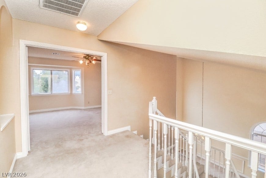 1429 Hawkwood Road, Henderson, NV 89014 An open landing features neutral carpeting and a white-railed staircase leading to the lower level.