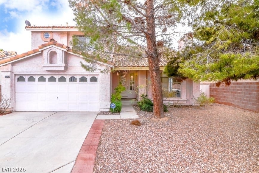 1429 Hawkwood Road, Henderson, NV 89014 Mature trees frame the front elevation of this two-story stucco home.