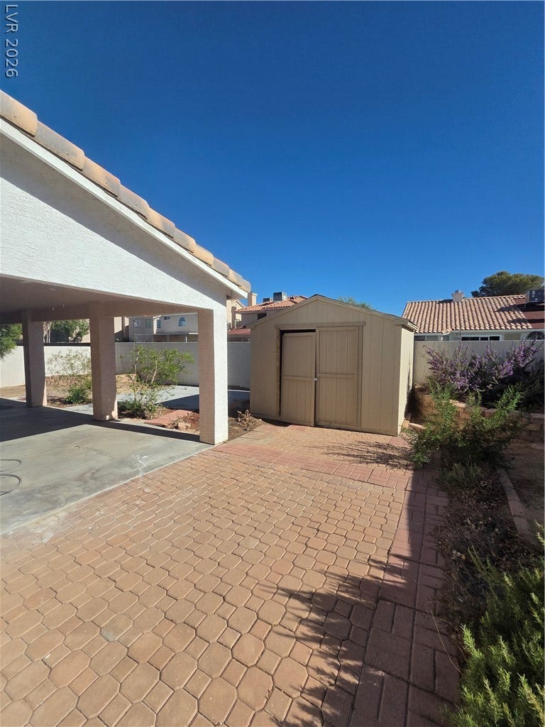 1429 Hawkwood Road, Henderson, NV 89014 A paved side yard features a detached storage shed set against desert landscaping.